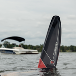Black Connelly Aspect water ski tip emerging from water, with a boat and trees in the background.