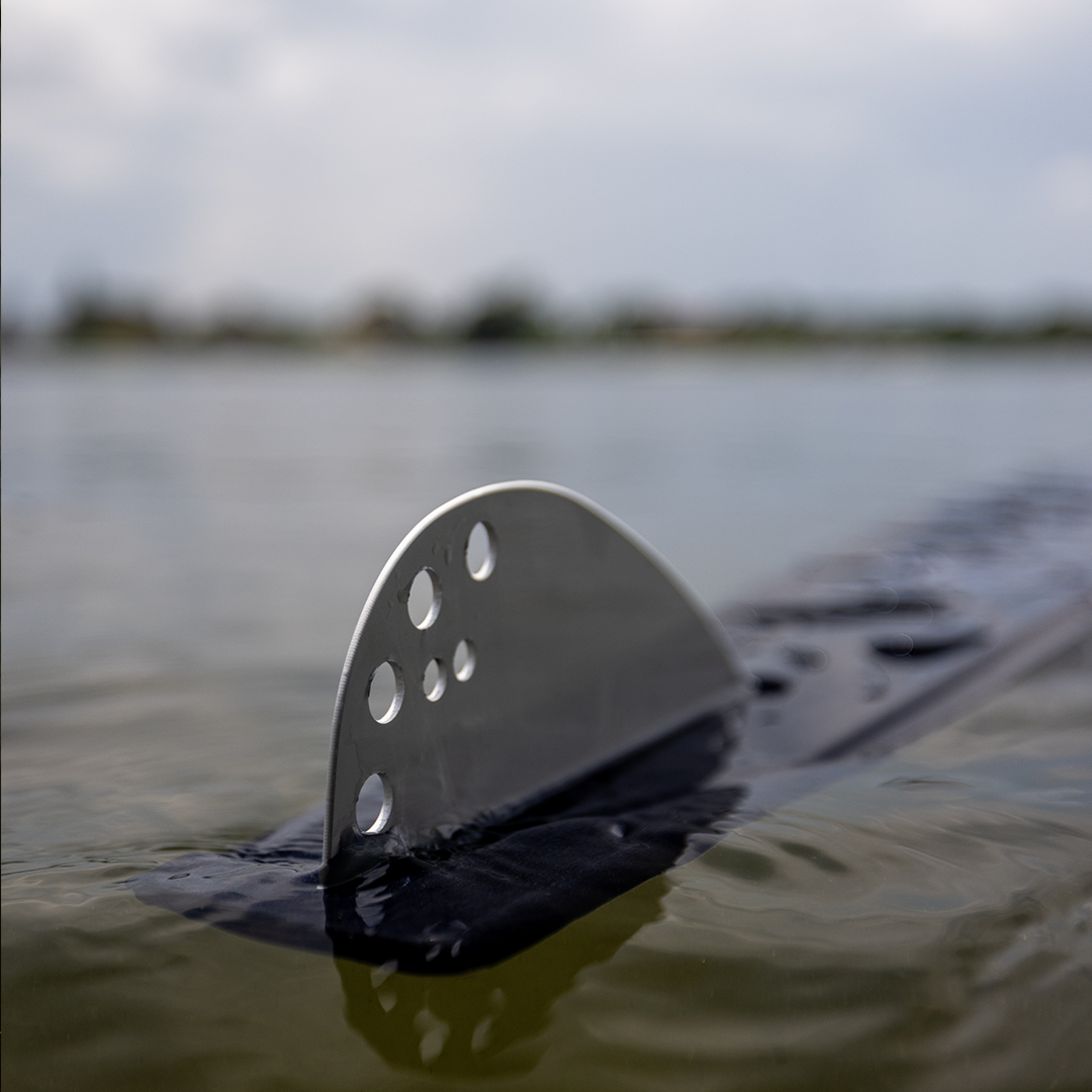 Close-up of the Aspect water ski fin with perforated design, partially submerged in water.