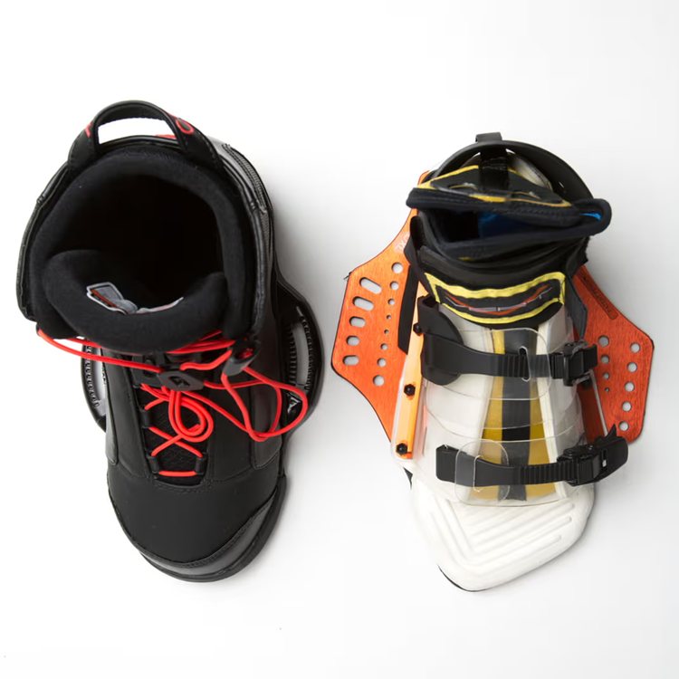 Snowboard boots and bindings, one black with red laces, the other white with orange accents.