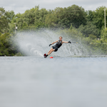 A water skier carving through a slalom course on a 2024 Carbon V ski, creating a powerful spray behind them.