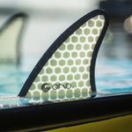 The Ono wakesurf board’s fin with a honeycomb design is partially submerged in water.