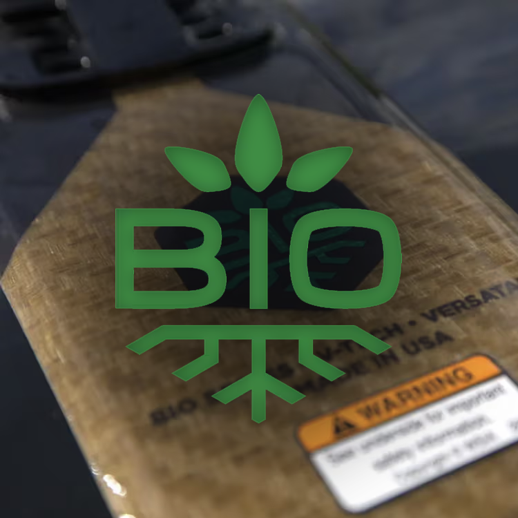 Close-up of a longboard with a green BIO leaf logo and warning label.