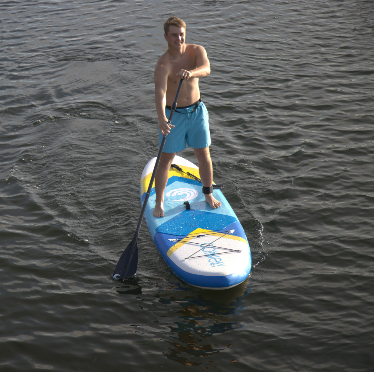 Front view of a man paddling the Tahoe ISUP, showcasing the chevron design and storage bungee.