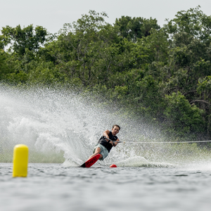 A male skier carves through the water on a Connelly 2024 Men's Concept ski, creating a large spray near course buoys.