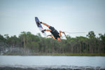 Action shot of a wakeboarder flipping mid-air while riding the PURE wakeboard on a lake.