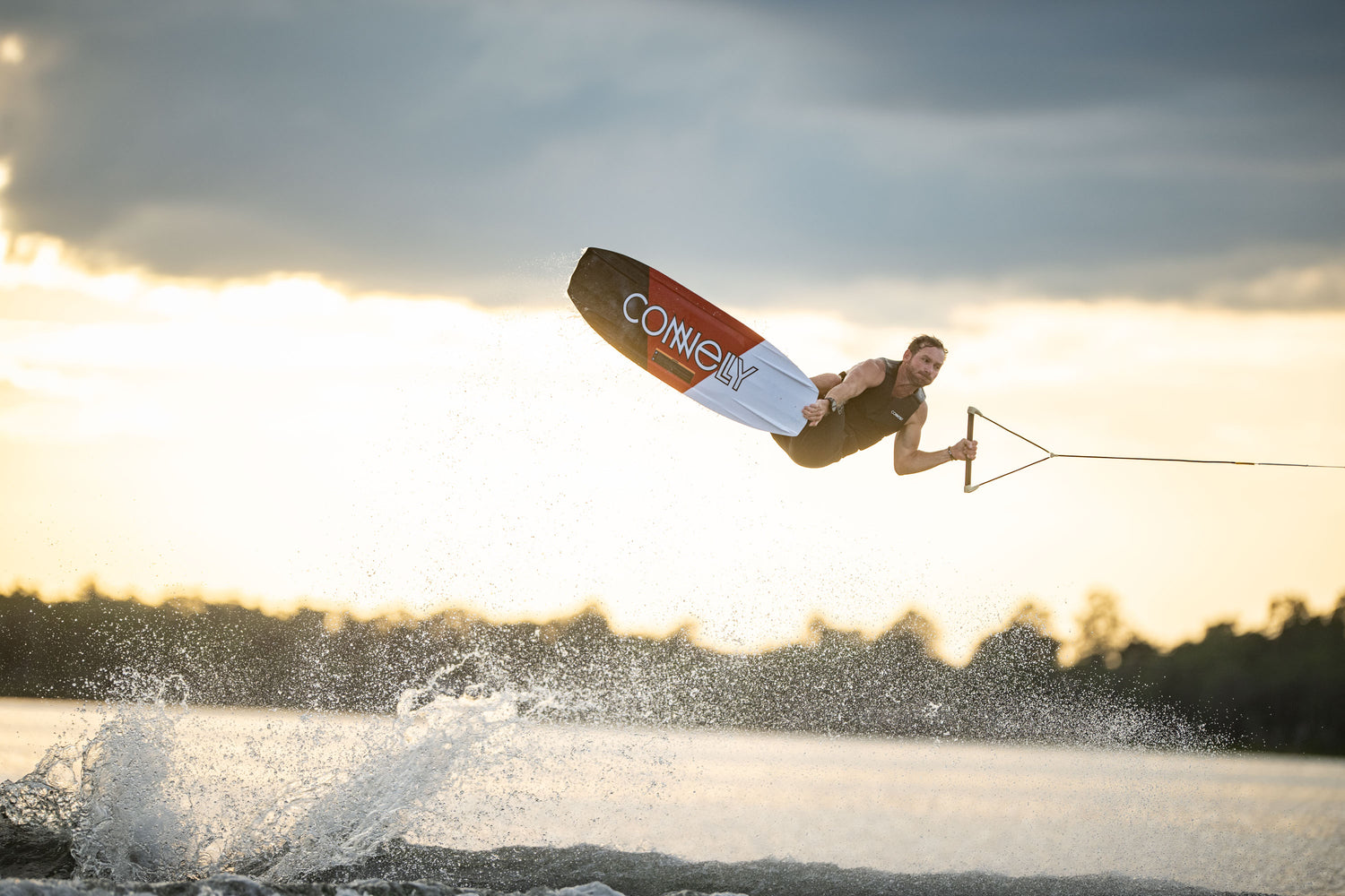 Action shot of a wakeboarder performing an aerial trick on the PURE wakeboard at sunset.