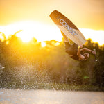 A wakeboarder performs an inverted aerial trick at sunset, showcasing the Connelly Big Easy wakeboard.