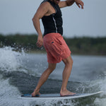 A male rider shifts his weight back on the Bentley board while wakesurfing, maintaining balance on the wave.