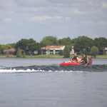Two riders sit back on the Big Easy 2 towable tube, gliding across the water behind a boat.