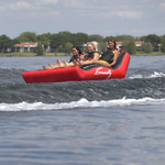 Three riders reclining on the Big Easy 3 tube as they glide over the water, with feet raised and secured by front handles.