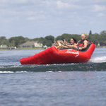 Big Easy 4 bouncing over a wake, with riders gripping tightly as the tube lifts into the air.