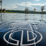 Close-up of the Boost kneeboard partially submerged in water, showcasing its glossy black and blue design details.