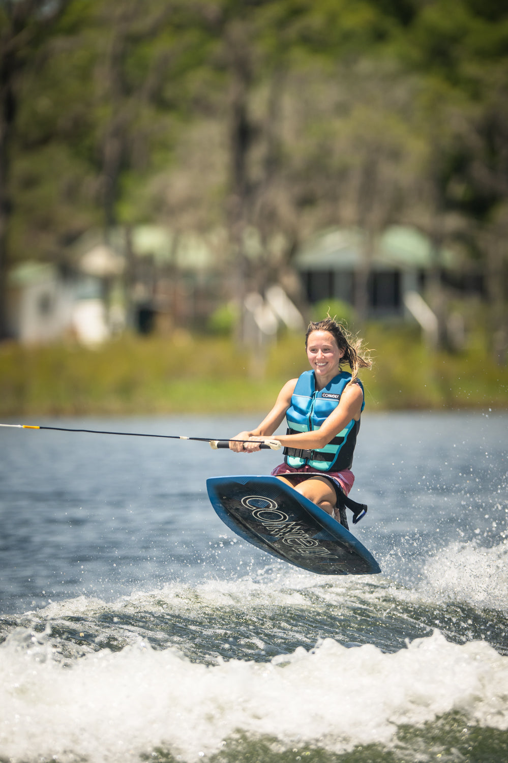 Rider in mid-air while kneeboarding on the Boost, gripping the handle and maintaining balance over the water’s wake.