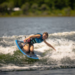 Rider wearing a blue vest carves through the water on the Boost kneeboard, gripping the handle and creating a spray.