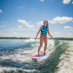 Young rider carving on the DASH Kid's Board, balancing on the wake while wearing a blue life vest.