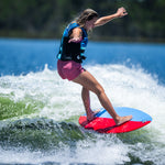 Young wakesurfer extending arms for balance while riding the DASH Kid's Board on a lake wave.