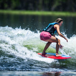 Young surfer crouching low on the DASH Kid's Board, maintaining balance on a breaking wave.