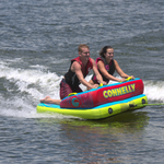Front view of the Fun 2 towable tube with two riders kneeling, gripping handles, and skimming across the water.