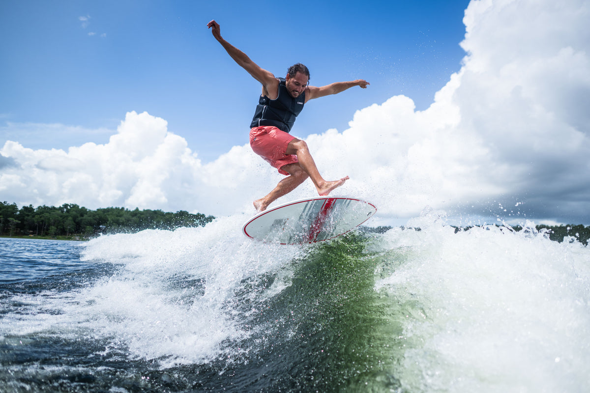 A rider catching air on the HABIT Skim wakesurf board, launching above the wave with arms outstretched.