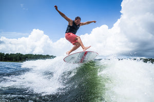 A rider catching air on the HABIT Skim wakesurf board, launching above the wave with arms outstretched.