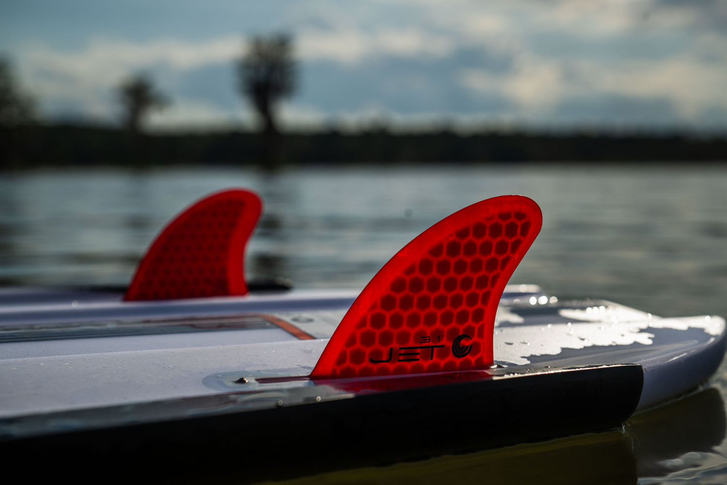 Red honeycomb-patterned Jet fins attached to the wakesurf board, designed for stability and precision in the water.