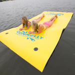 Top-down view of two women lounging on the yellow Party Cove Island with blue branding and water droplets on the surface.