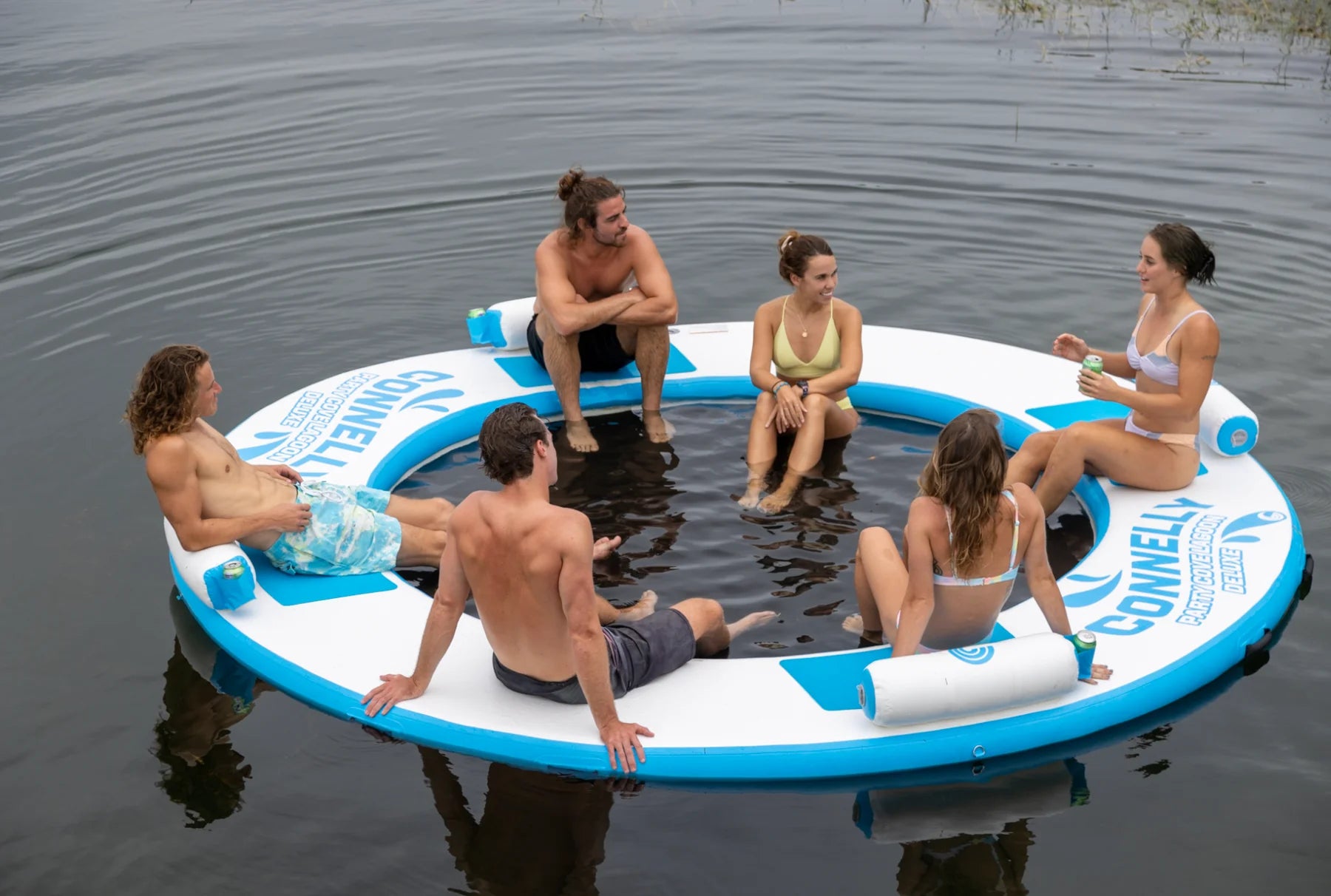 People relaxing on a large, round float in the water.