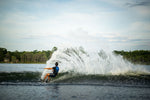 Rider carving a powerful turn on a Blaze wakeboard, creating a dramatic spray of water behind them.