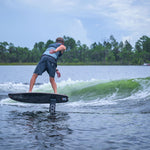 Person wakefoiling on a lake with trees and sky in the background.