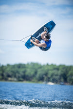 Rider executing an aerial trick on a Blaze wakeboard, soaring above the water with a blue sky in the background.