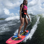 Woman riding the SPARK wakesurf board on a wave, balancing with bent knees and arms extended.