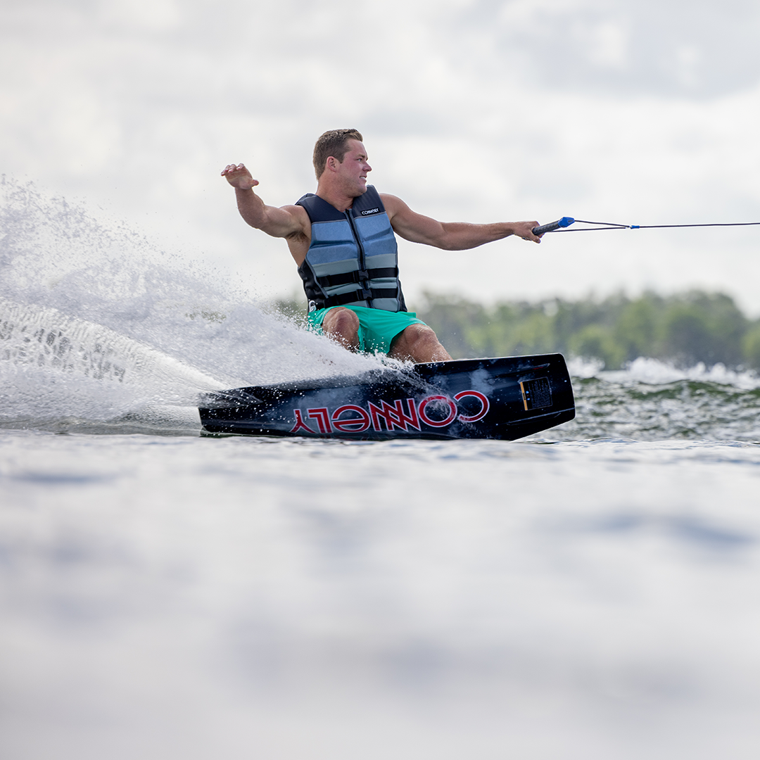 Wakeboarder carving on the Connelly 2024 Standard, creating a spray of water while riding with a relaxed stance.