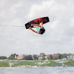 Wakeboarder performing an aerial trick, flipping over the water while riding the Connelly 2024 Standard wakeboard.