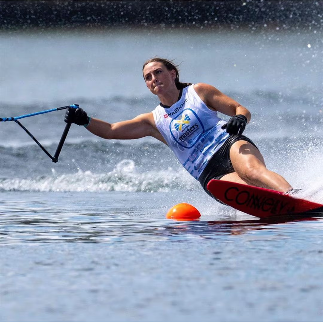 Person waterskiing on one ski near an orange buoy in a lake.