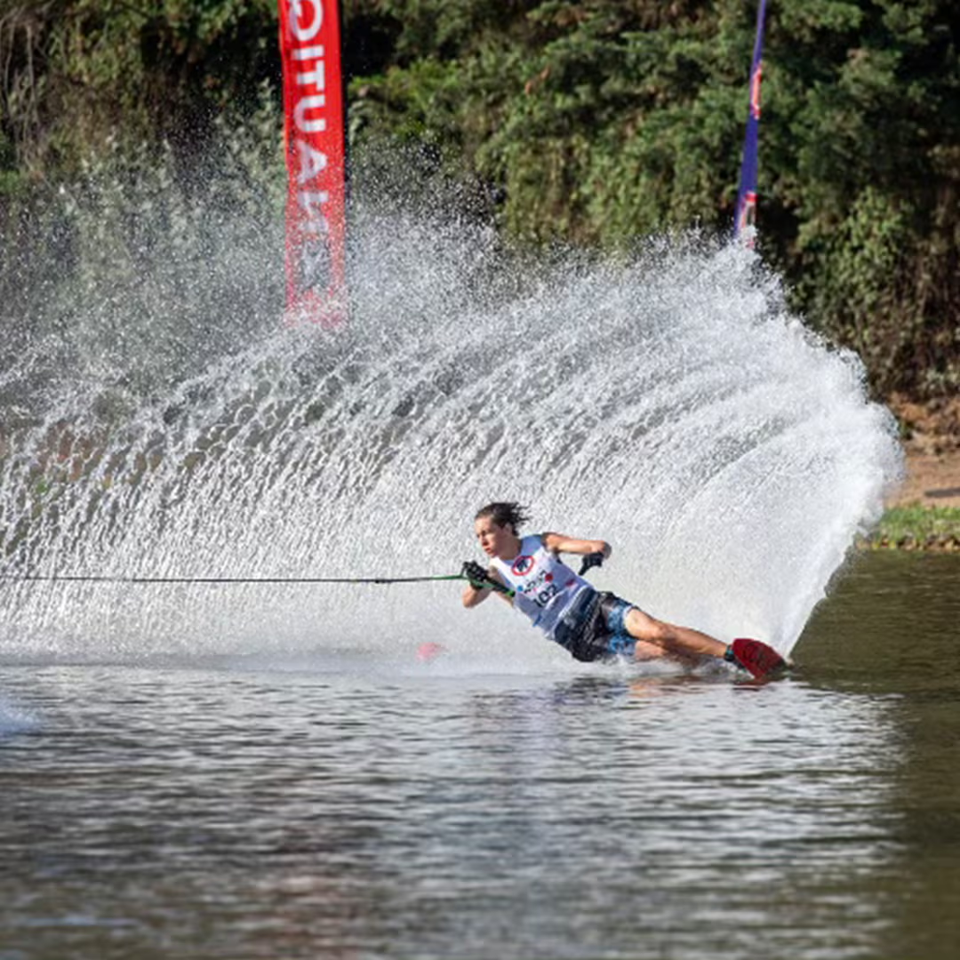 Person waterskiing, creating a large spray of water behind them on a sunny day.