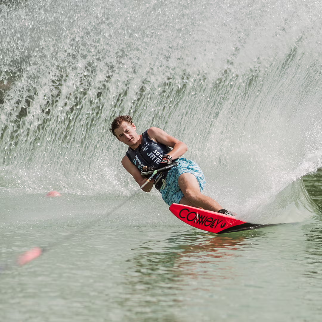 Person water skiing, leaning back, creating a large spray of water behind them.