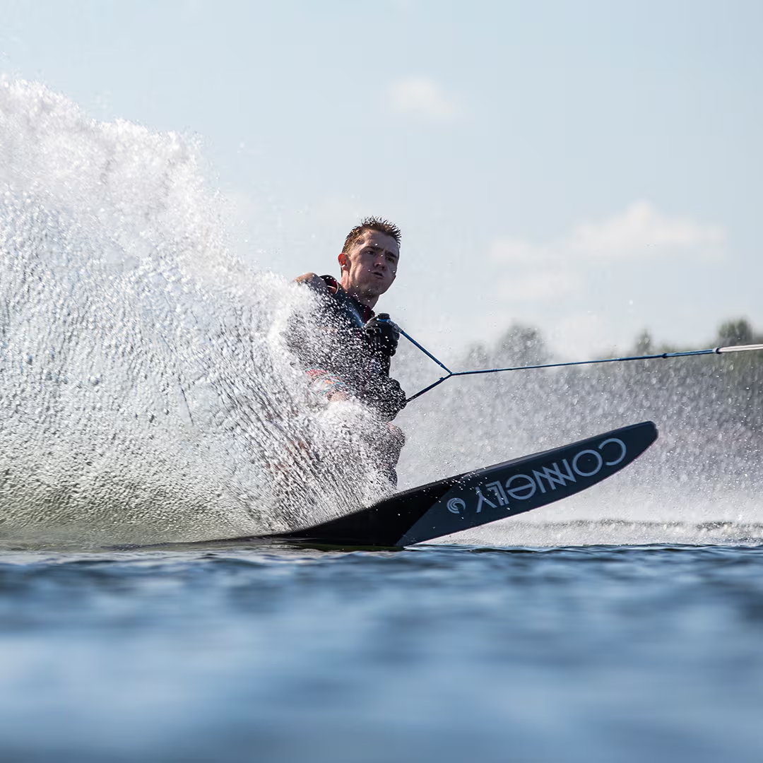 Person water skiing, creating big spray on a sunny day.