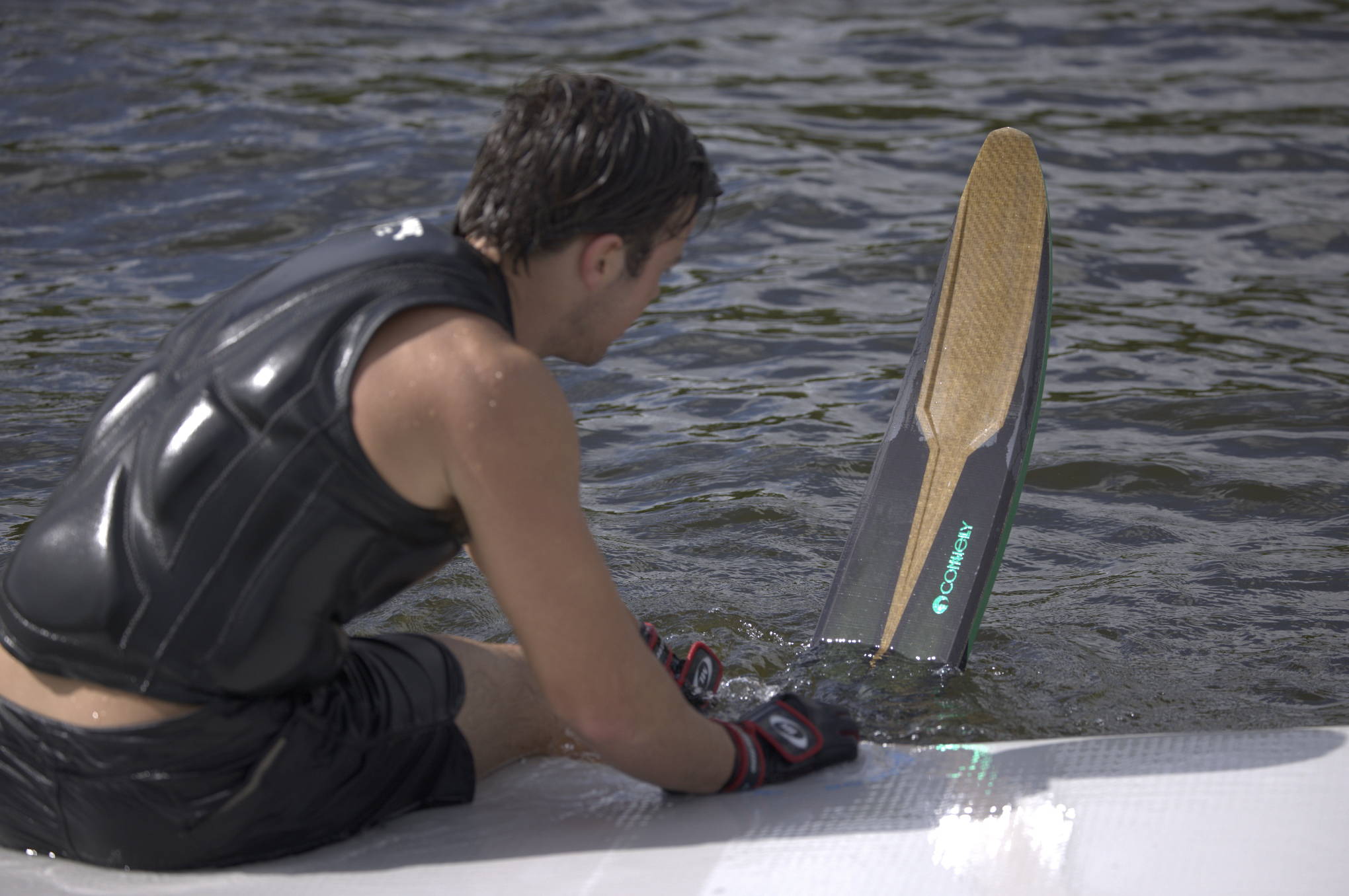 Person in a life vest holding a wakeboard on the water.