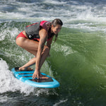 A rider in a red swimsuit surfing on the Stratus board, balancing on a wave with a focused stance.