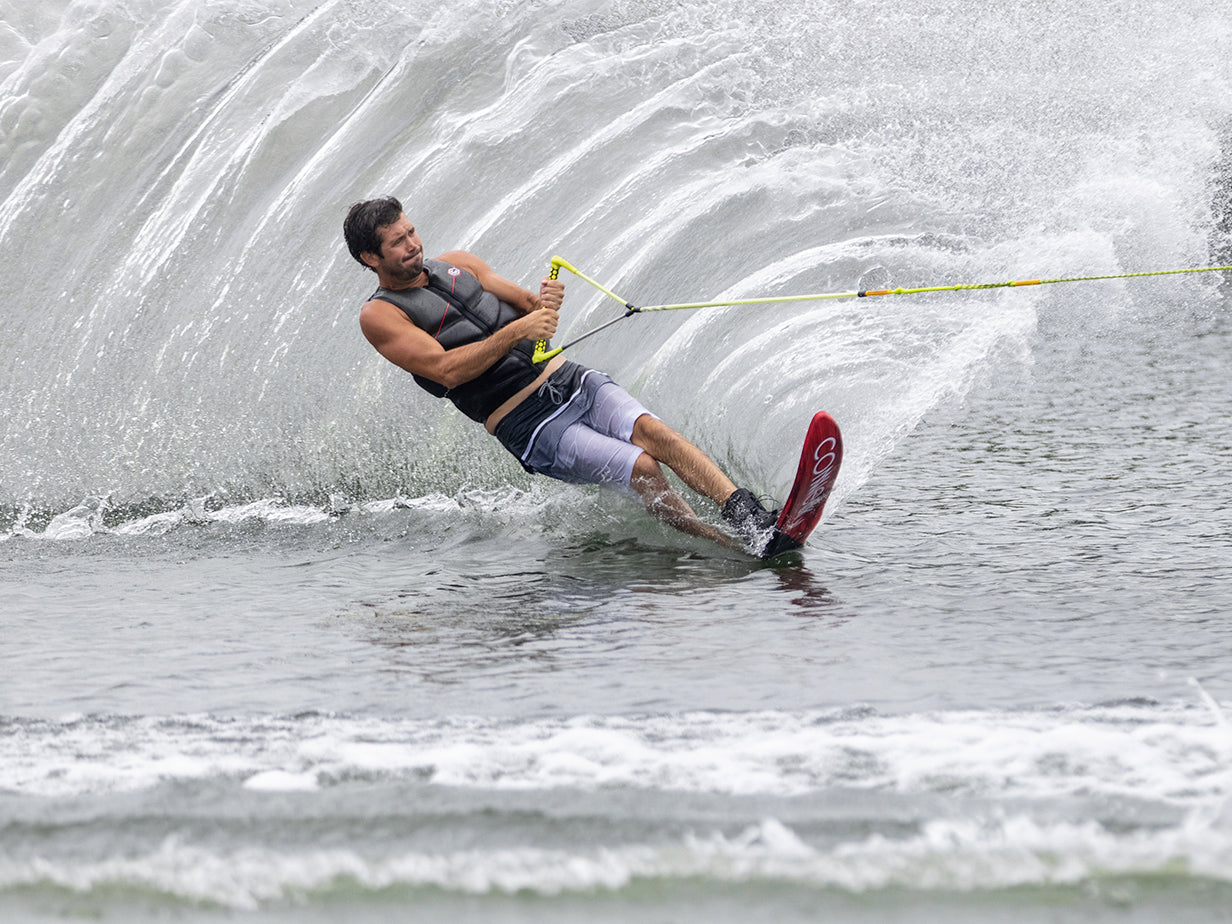 Skiing on a lake with mounted 2022 Outlaw skis, creating a large splash behind them.