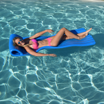 Poolside view of a woman on the Party Cove Lounge, floating on water with its contoured design and cushioned headrest.