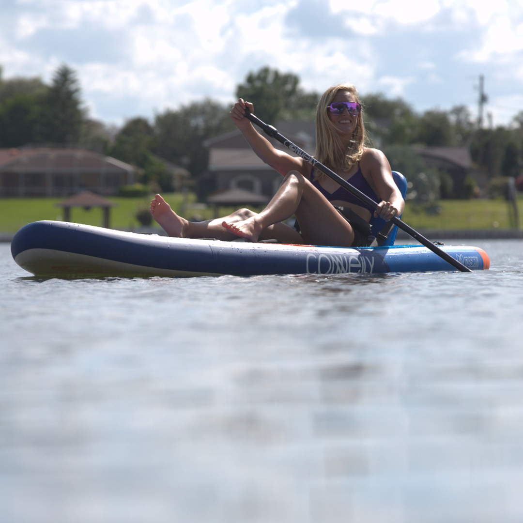 A woman reclines on the Pacific ISUP, paddling in a relaxed seated position.